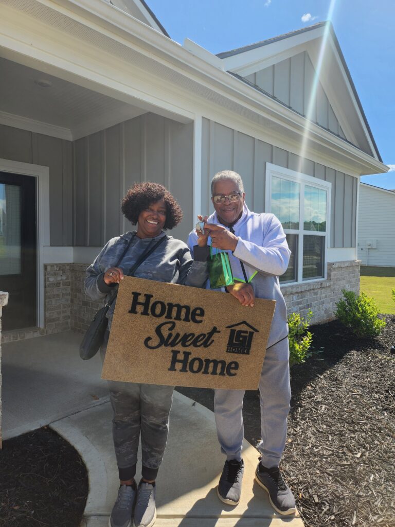 A couple holding a Home Sweet Home sign