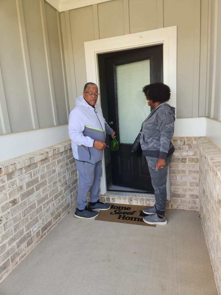 A couple standing a the front door of a house.